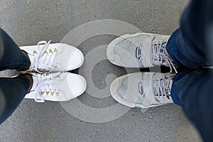 Top view of two pairs of sneakers shoes, legs of loving couple