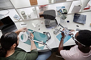 Two People Fixing Drones at Table in Tech Repair Shop