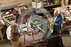 Top view at two people refurbishing furniture in workshop