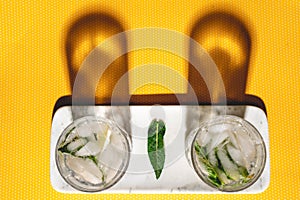 Top view of two perfect mojito cocktails on vintage yellow dots background and hard shadows