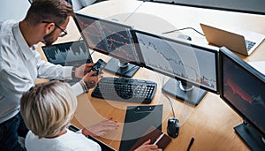 Top view. Two stockbrokers in formal clothes works in the office with financial market