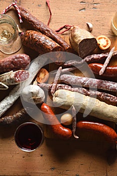 Top view of typical spanish sausages and red and white wine on wooden