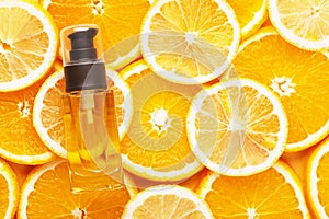 Top view of unbranded glass container with oil for hair. Transparent bottle with dispenser. Juicy slices of orange and lemon on