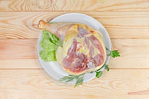 Top view of uncooked broiler chicken leg quarter with greens