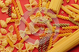 Top view of uncooked italian pasta isolated on orange. Different types of pasta, macro view