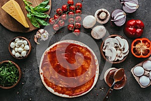 Top view of uncooked pizza dough with sauce and vegetables