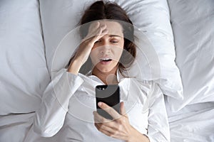 Top view unhappy woman using phone, bad news, oversleep