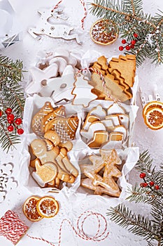 Top view of unpacked christmas present with sweets on a white textured surface framed by fir branches, close-up.