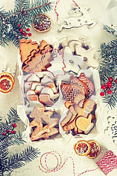 Top view of unpacked christmas present with sweets on a white textured surface framed by fir branches, close-up.