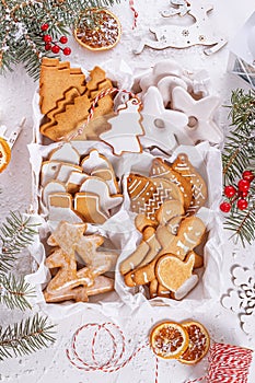 Top view of unpacked christmas present with sweets on a white textured surface framed by fir branches, close-up