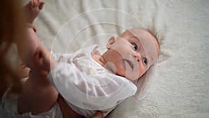 Top view of unrecognizable caring mother dressing newborn baby girl in bodysuit lying on changing table. Concept of