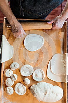 Top View of Unrecognizable Hispanic Woman Kneading Dough with Hands and Rolling Pin in Her Countryside Kitchen photo