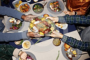 Male Hands Passing Cooked Turkey at Dining Table while Eating at Christmas Dinner photo