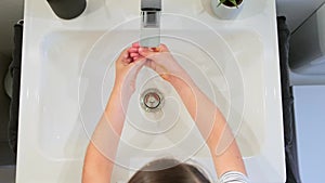 Top view of unrecognizable woman washing golden glitter of her hands into a washbasin at bathroom