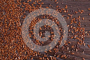 Top view of unsorted flax seeds on dark wooden table, seasonings for food, healthy eating.