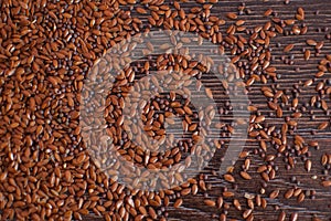 Top view of unsorted flax seeds on dark wooden table, seasonings for food, healthy eating.