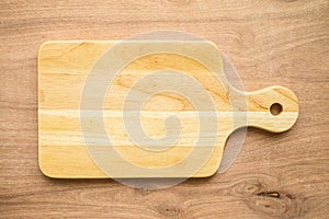 Top view of unused brand new brown handmade wooden cutting board on wooden table background