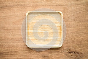 Top view of unused brand new brown handmade wooden dish plate on wooden table background