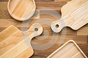 Top view of unused brand new brown handmade wooden kitchen utensil, dish plate and cutting board on wooden table background