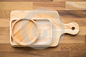 Top view of unused brand new brown handmade wooden kitchen utensil, dish plate and cutting board on wooden table background