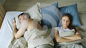 Top view of upset lying sleepless couple in bed offended because of quarrel