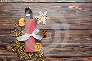 Top view of utensils on festive napkin on wooden background. Christmas decorations with dried fruits and cinnamon. New year dinner