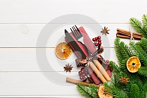 Top view of utensils on festive napkin on wooden background. Christmas decorations with dried fruits and cinnamon. New year dinner