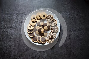 Top view of variety of cookies in a plate on a background