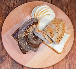 Top view of various bread on round wooden serving board