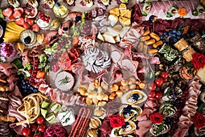 A top view of various food and snacks on a tray on a indoor party, a cold buffet.