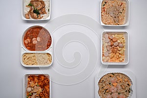 Top view various frozen meal in plastic tray against white background.