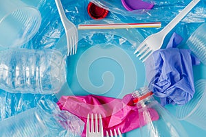 Top view of various kinds of disposable plastic waste on blue background, copy space