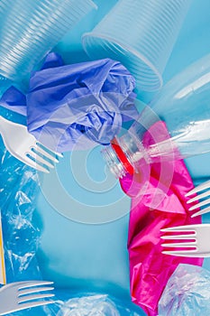 Top view of various kinds of disposable plastic waste on blue background, copy space