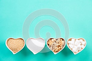 Top view of various types of sugar. Cube sugar, raw sugar brown sugar and granulated sugar in heart bowl on bright green pastel