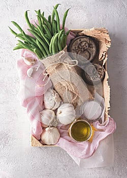 Top view of a vegetable box with garlic, oil, and green beans