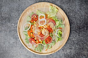 Top view vegetables salad with shrimps on wooden plate.