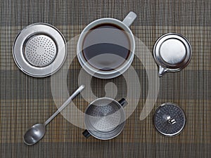 Top view of vietnamese coffee filter ingredients with ready cup of coffee on bamboo placemat