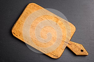 Top view of vinatge wooden cutting board on black slate stone background