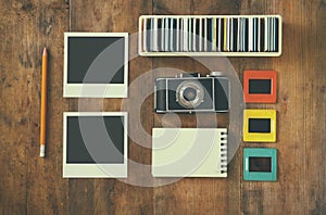 Top view of vintage camera and old slides frames over wooden table background