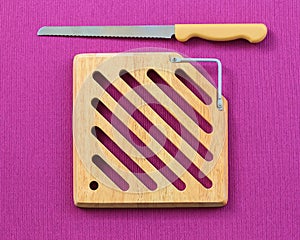 Top view vintage cutting bread wood block and tray with stainless stell knife on purple tablecloth background