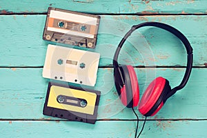 Top view of vintage headphones and cassettes over aqua wooden table. retro filtered