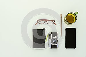 Top view of vintage photo camera with notepad, prescription glasses, teacup