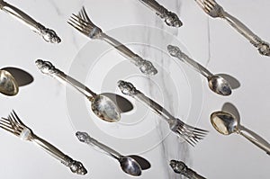 Top view of vintage spoons and forks on the white marble table.Bright light and shadows