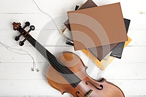 Top view of violin with stack of book and earphone