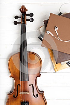 Top view of violin with stack of book and earphone