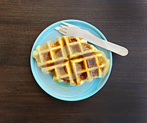 Top view of waffle topped with honey sauce on blue plate at cafe. Flat lay of Sweet bakery on dish