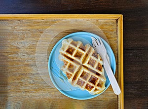 Top view of waffle topped with honey sauce on blue plate at cafe. Flat lay of Sweet bakery on dish.