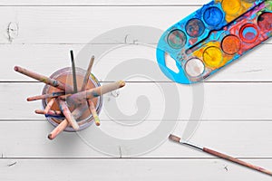 Top view of water crayons and paint brushes in a jar with paint