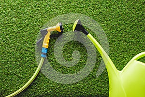 top view of watering can and hosepipe on grass, minimalistic conception