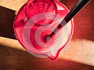 Top view of wetting a mop in red bucket of water